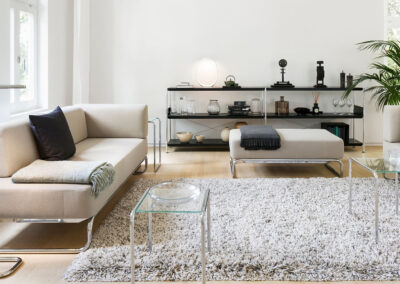 Soggiorno luminoso con divani bianchi, tavolini in vetro e decorazioni eleganti, ideale per ambienti.